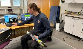 Biomekaanikko Volter Pietarinen istuu tutkimuslaboratoriossa tietokoneen äärellä rullasuksi sylissään.