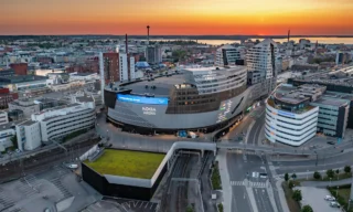 Ilmakuva Nokia Areenasta Tampereella. Taustalla värikäs auringonlasku.